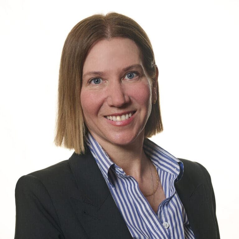 Headshot of Julija Hunter, a senior consultant at Bizcom wearing a gray jaket and a blue striped collared shirt.